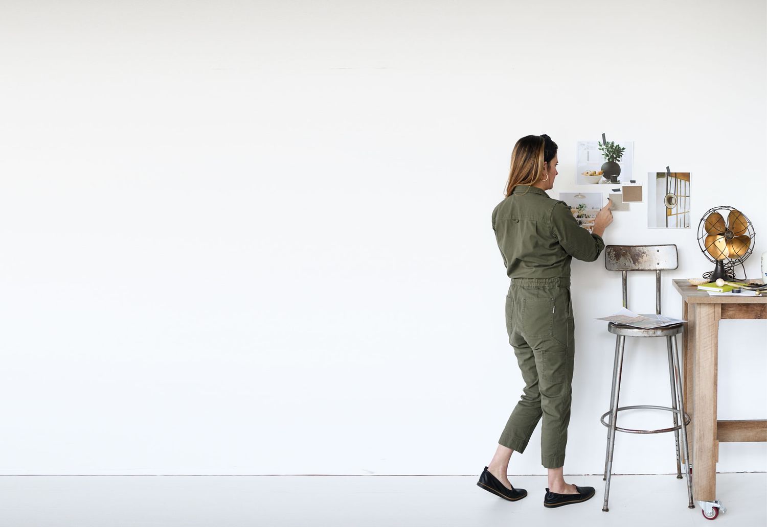 Minimalist white workspace with desk, stool and decorative elements in clean design.