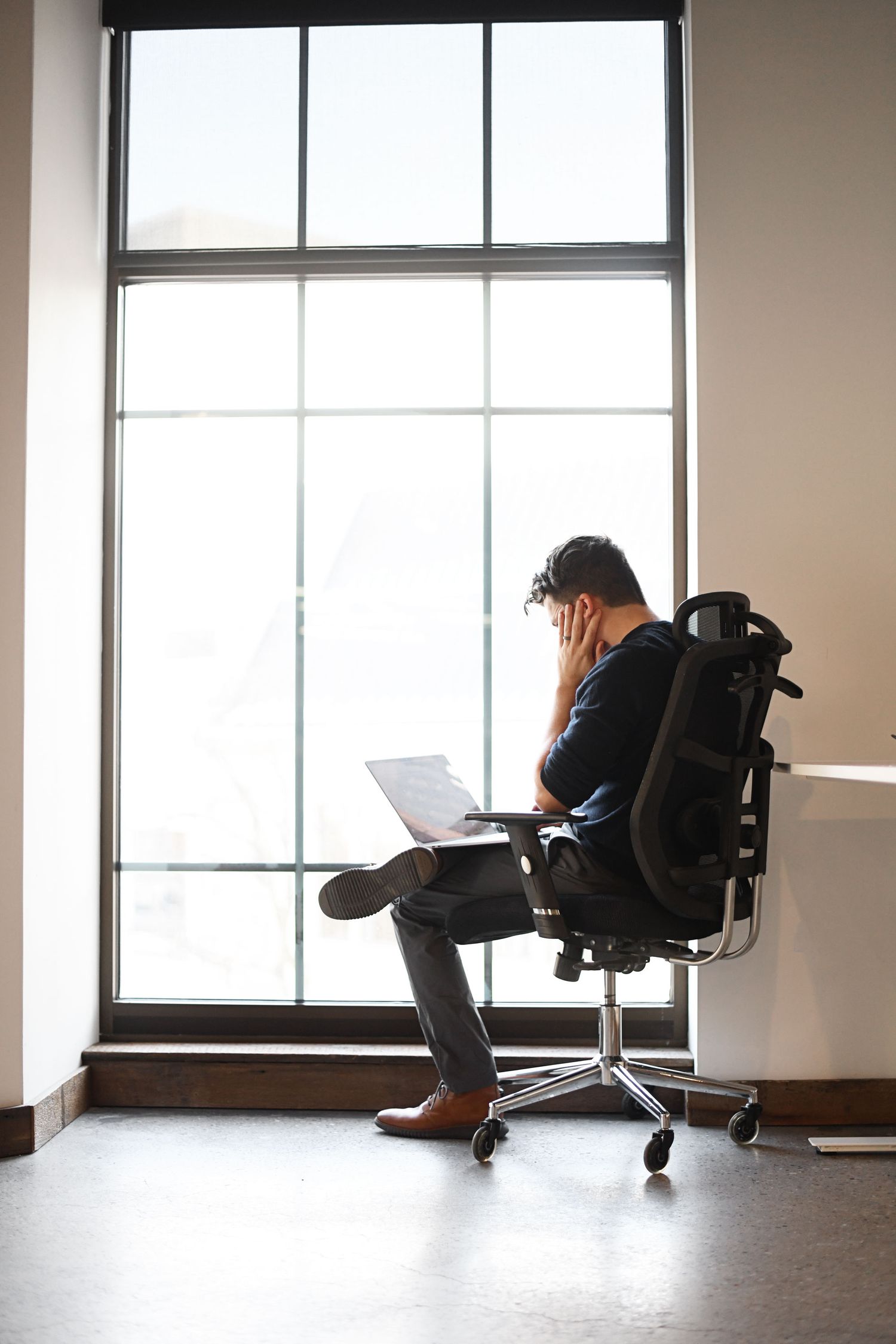 Silhouetted figure sitting in modern office chair by large windows in progressive sequence.