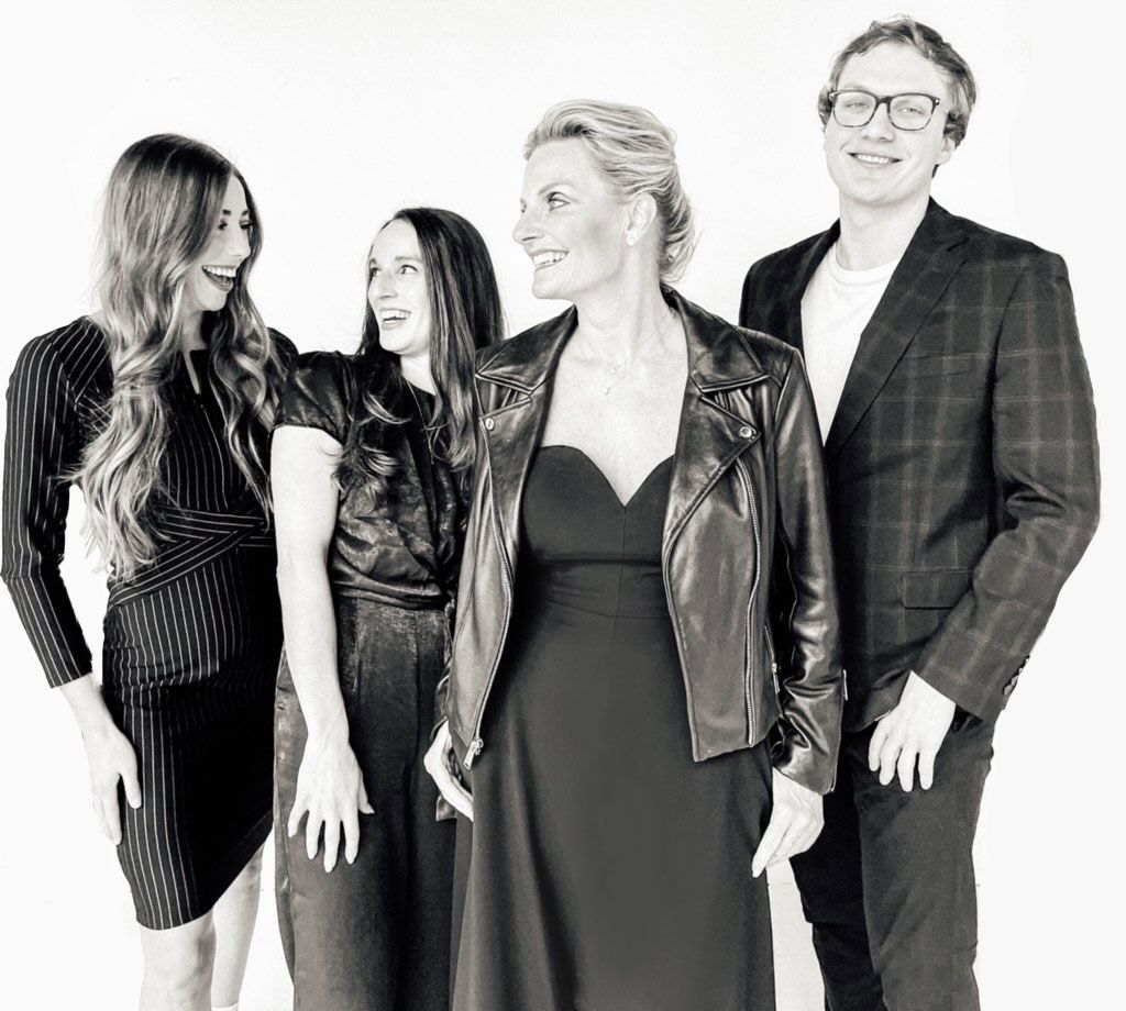 Black and white group portrait showing stylish individuals in professional attire against white background.