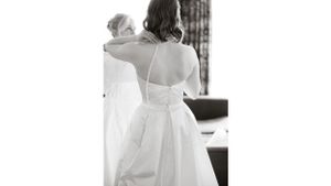 Back view of elegant white wedding dress with delicate lace details and buttons.