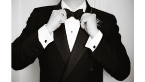 Close-up of formal black tuxedo with bow tie being adjusted.