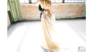 Ethereal bridal portrait in sunlit industrial space with flowing dress.