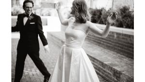 Playful black and white wedding dance photo on urban rooftop.
