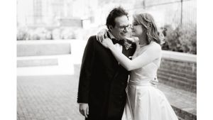 A romantic black and white portrait of a couple in wedding attire sharing an intimate moment.