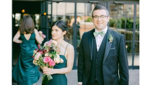 A couple in formal attire at a wedding, with the bridesmaid holding a vibrant pink bouquet.