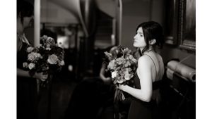 Person in formal attire holding beautiful floral bouquet in black and white portrait.