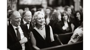 Formal event attendees seated in wooden pews during ceremony.