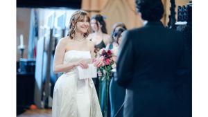 Bride in white dress holding bouquet during indoor ceremony.