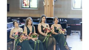 Bridesmaids in dark gowns holding floral bouquets seated in church pews.
