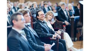 Wedding guests seated in formal attire during indoor ceremony.