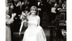 Black and white photo of bride celebrating with bouquet.