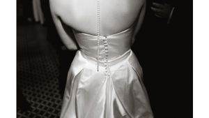 Back view of a white satin wedding dress with delicate button details.