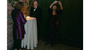 Evening event scene with candlelit table and photographer capturing the moment.