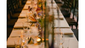 Long formal dining table set with glassware and floral centerpieces.