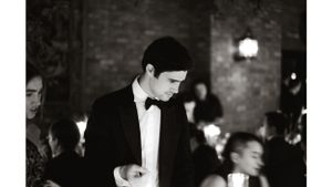 Formal event guest in black tie attire at an elegant brick-walled venue.