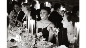 Elegant dinner party scene with candlelight and formal place settings at a black-tie event.