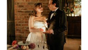 Bride in strapless gown shares a tender moment with groom against rustic brick backdrop.