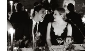 Couple sharing animated conversation at an elegant candlelit dinner table.