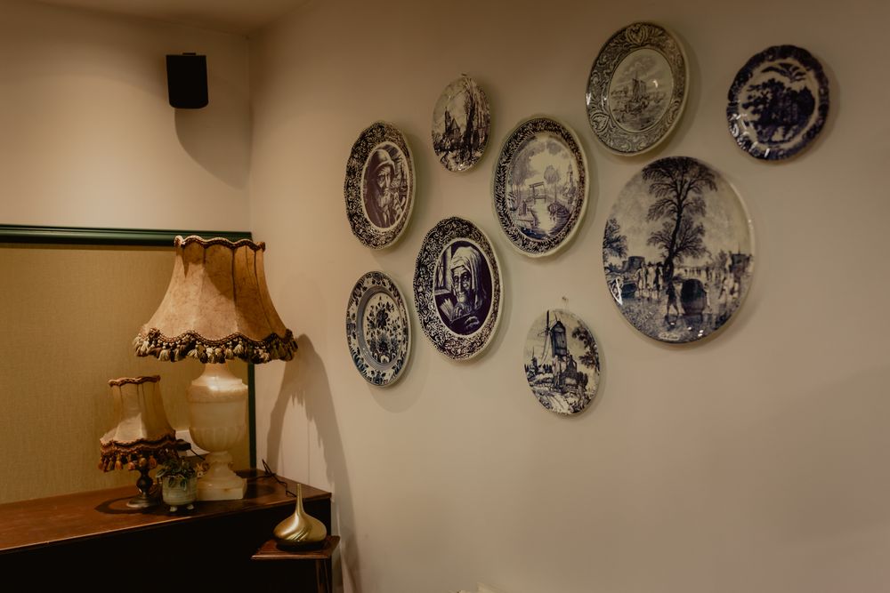 Decorative blue and white Delft plates arranged on cream wall with vintage table lamp.