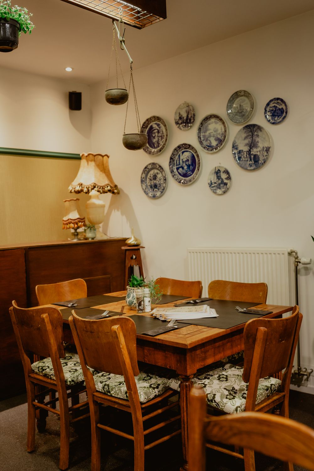 Restaurant dining table with wooden chairs and decorative blue plates displayed on wall.