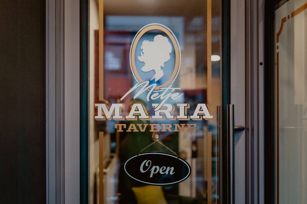 Storefront window displaying 'Mize Maria' logo with classic cameo design and 'Open' sign.