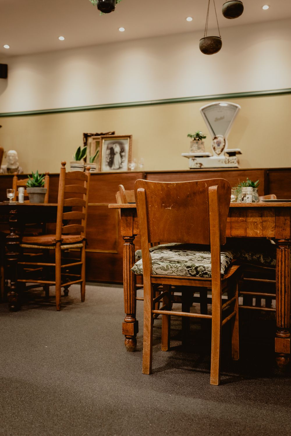 Rustic dining room interior with wooden chairs and wainscoting in warm lighting.