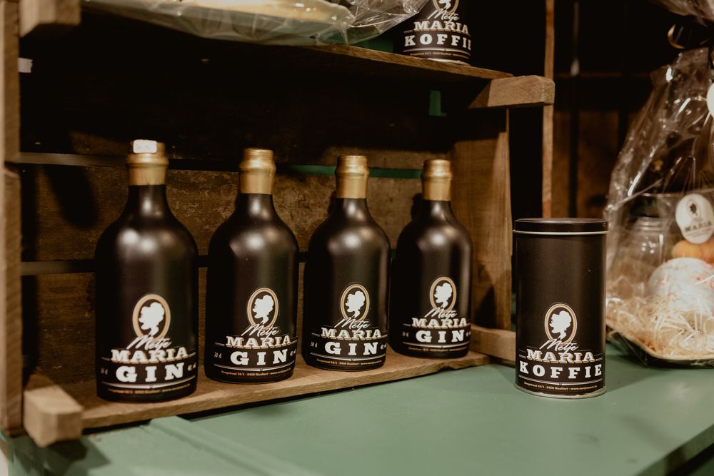 Row of dark glass gin bottles with white labels displayed on a green shelf.