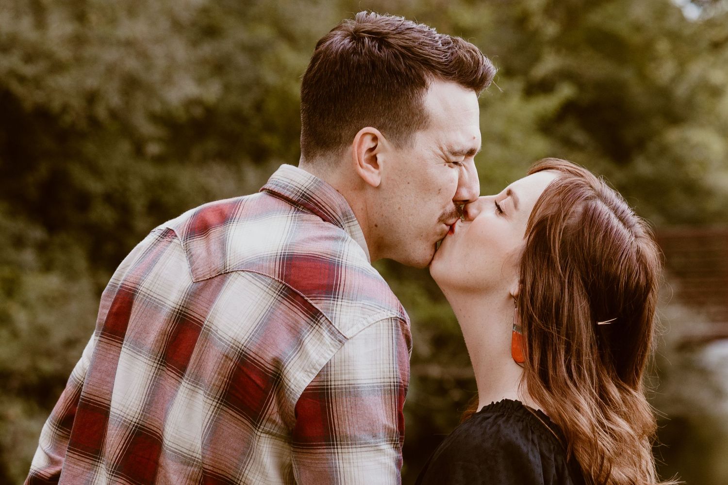 Intimate moment shared between couple in casual attire by a stream.