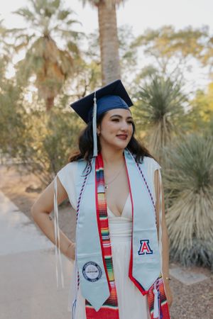 Graduate wearing University of Arizona stole and graduation cap with colorful serape sash.