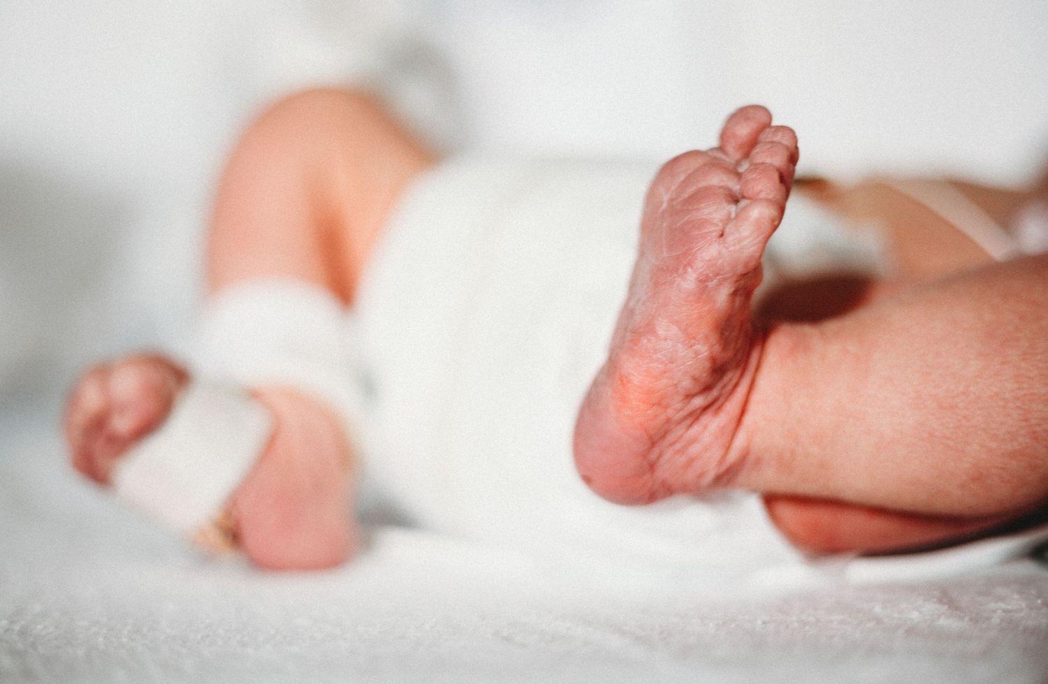 Close-up detail shots of newborn baby feet against white background.