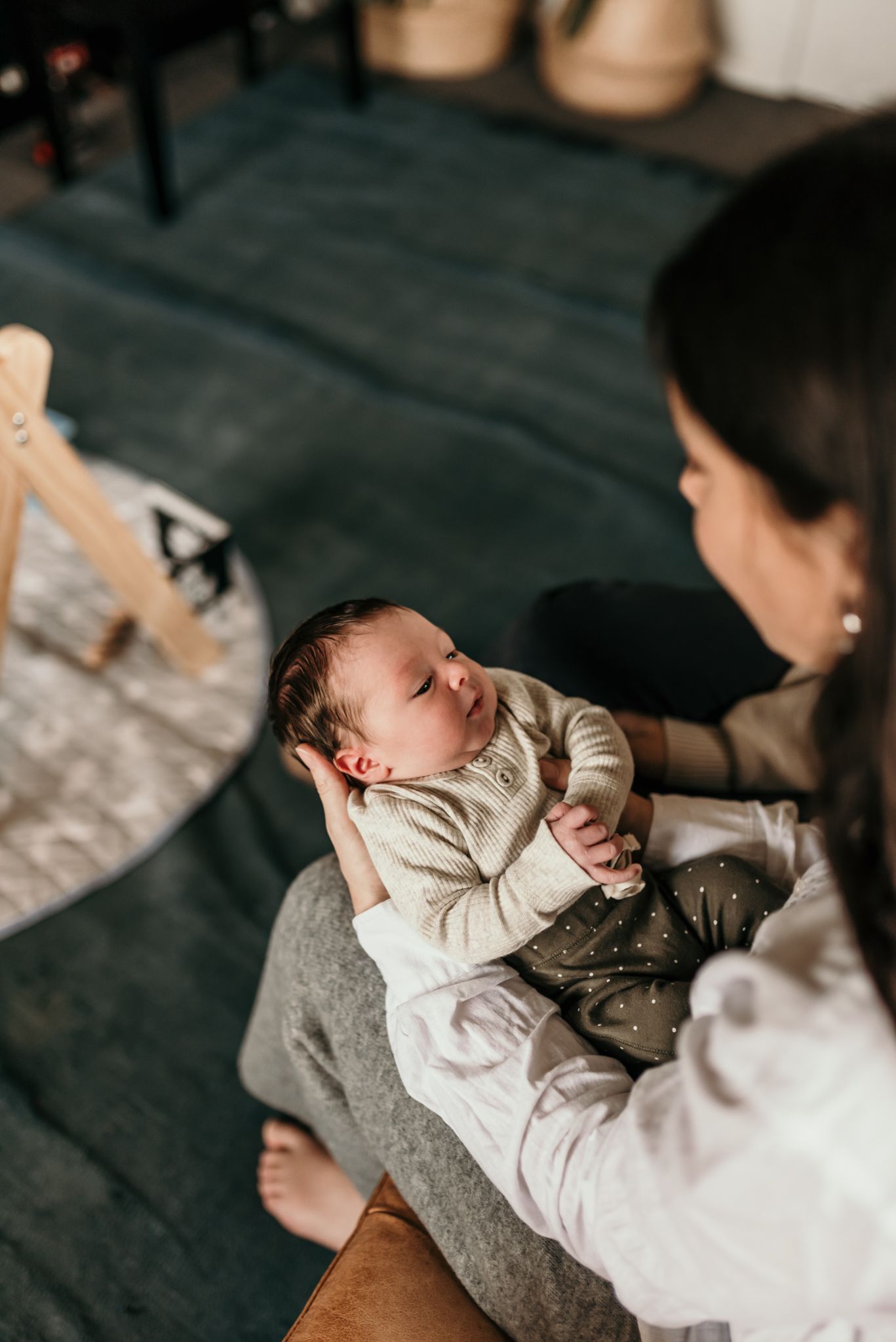 Sweet newborn baby sleeps peacefully on a grey blanket while being cradled in a tender moment.