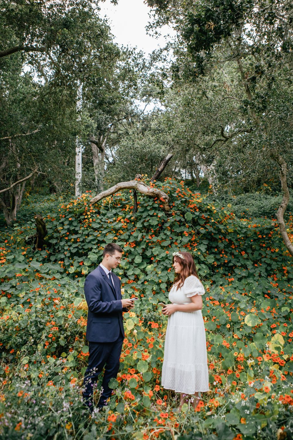 Couple shares tender moments in a garden filled with vibrant orange flowers and greenery.