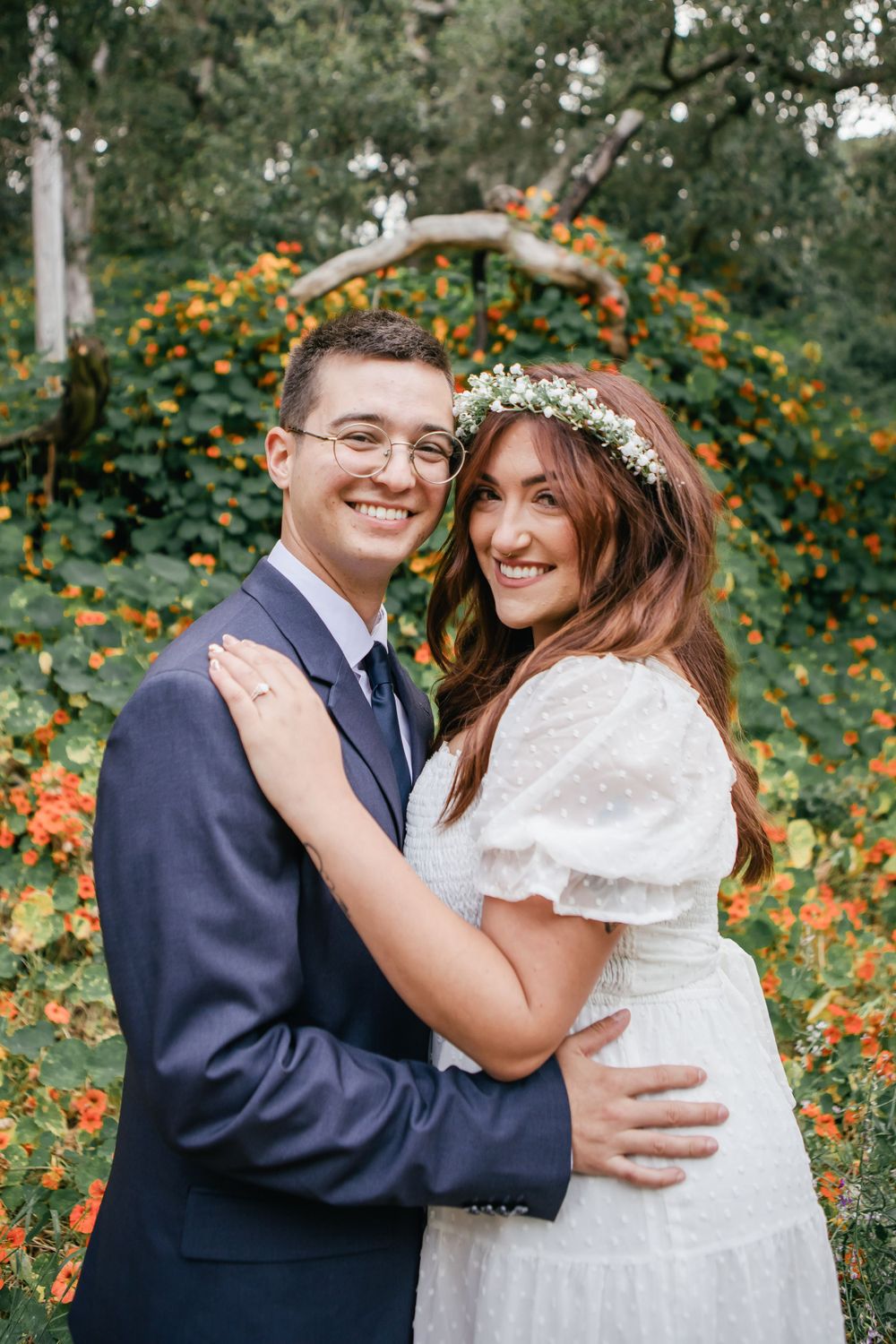 Sweet embrace captured in a garden setting with orange flowers and natural greenery.