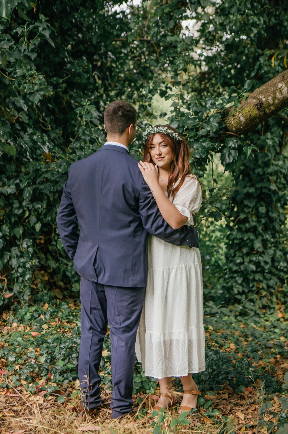 Couple shares tender moments among green foliage and orange flowers in a garden.