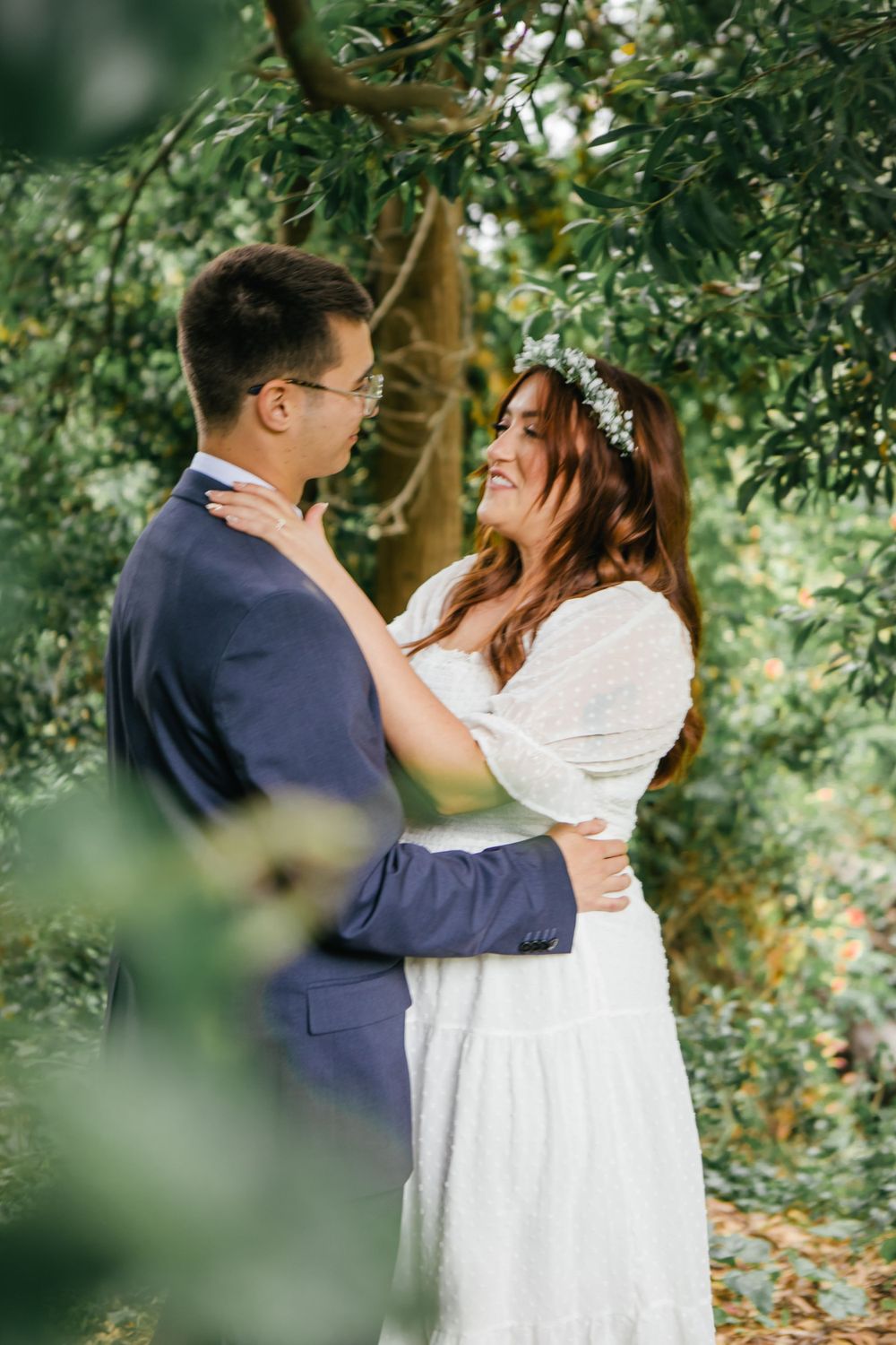 Couple embraces and shares tender moments surrounded by lush garden foliage.