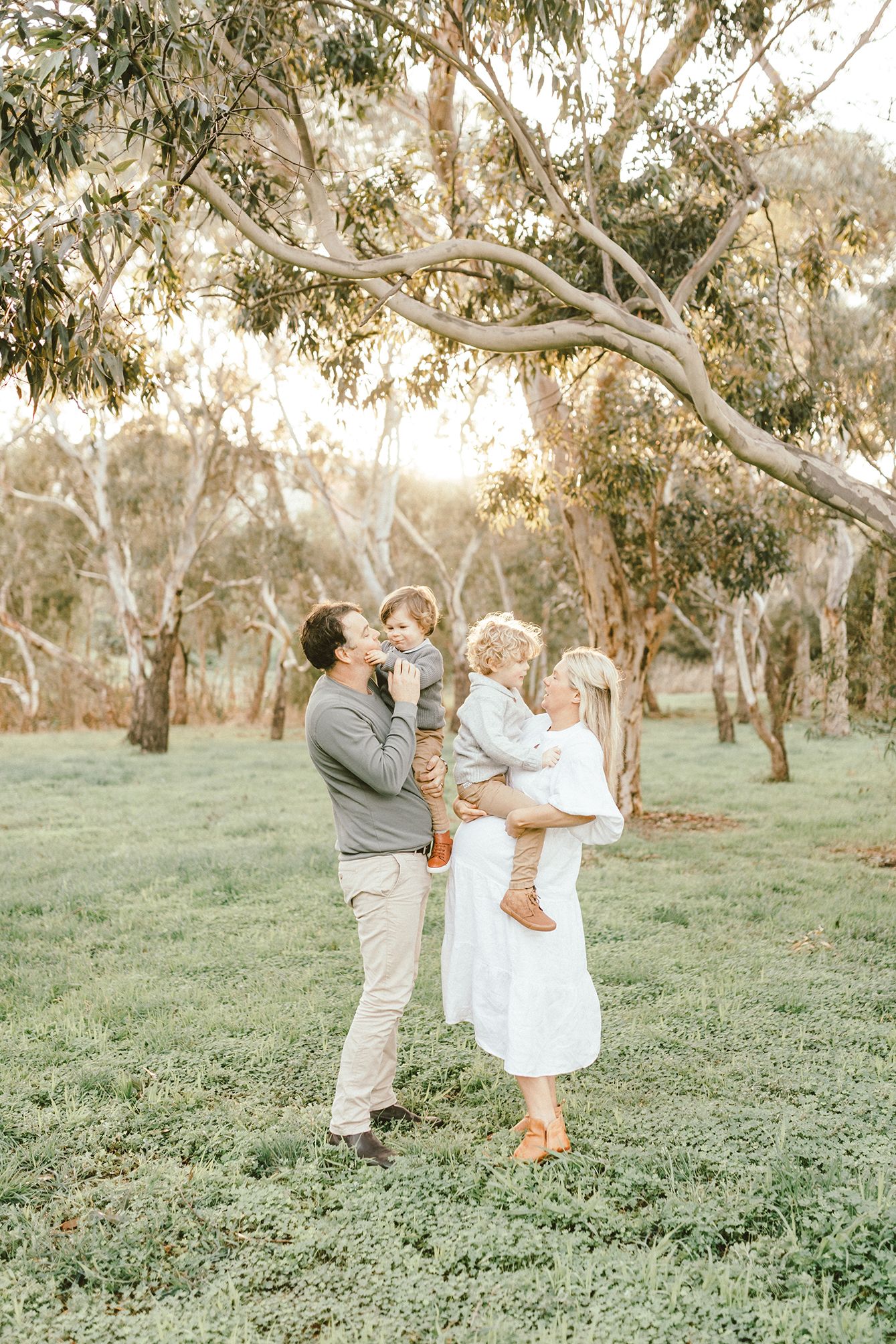 Family sharing joyful moment together in a sunlit eucalyptus grove.