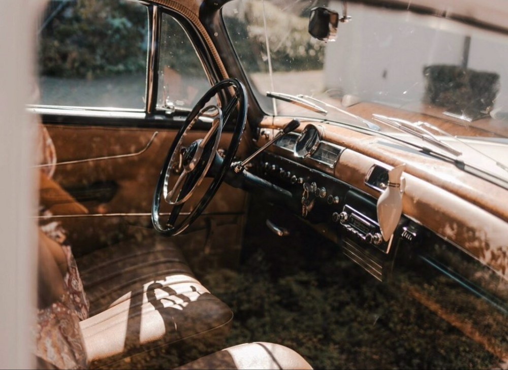 Vintage car interior dashboard showing classic analog gauges and steering wheel.
