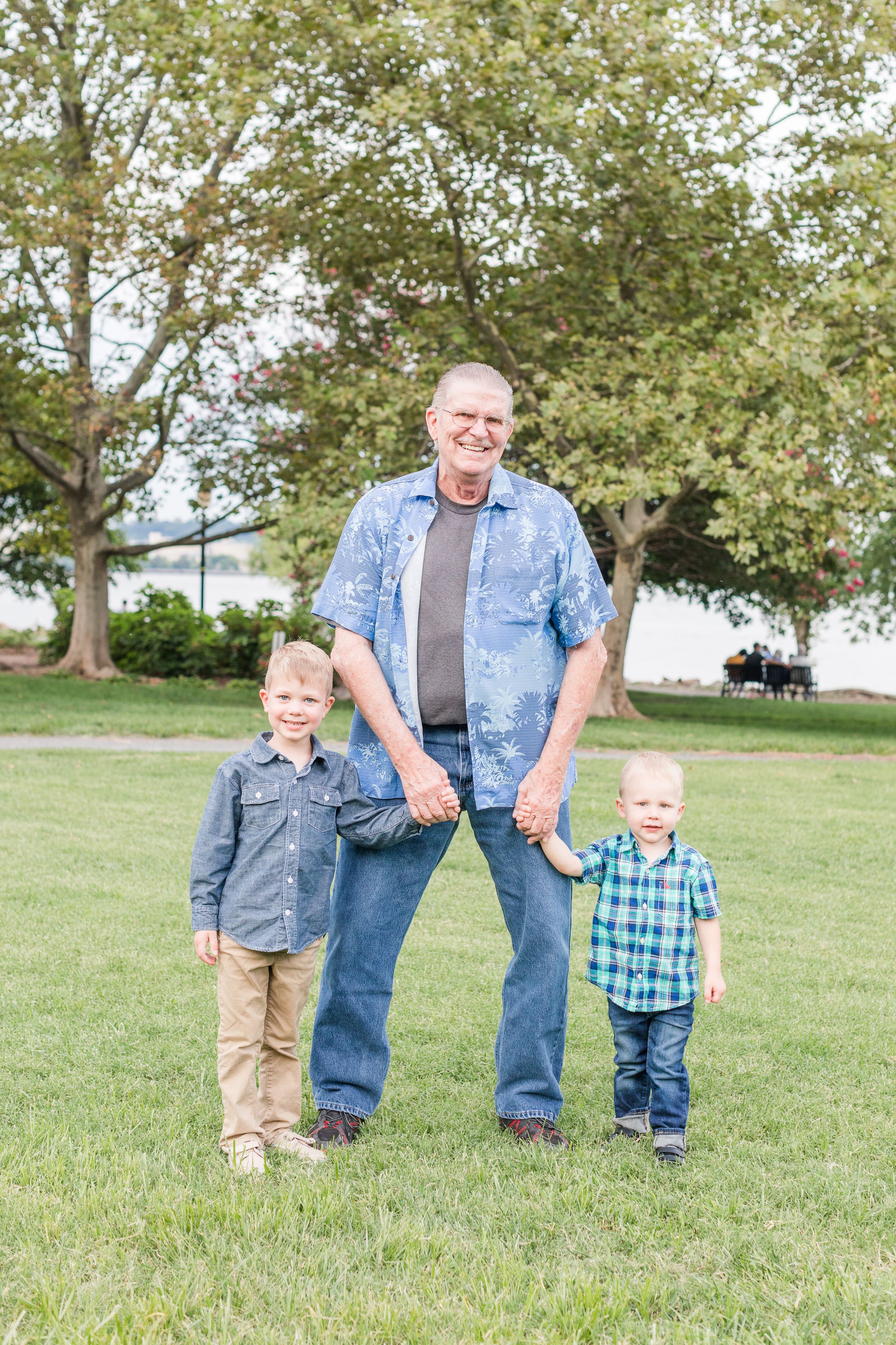 Grandpa posing with small grandsons in Founders Park Old Town Alexandria in summer