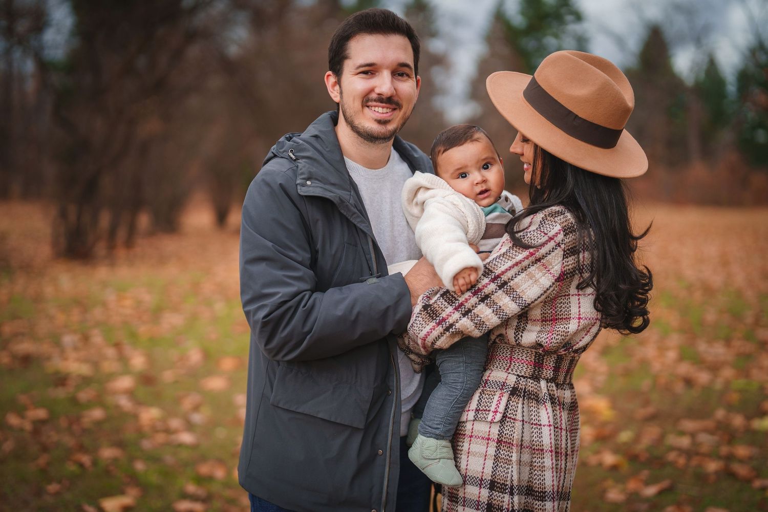 Loving family embraces while standing together in a fall forest setting.