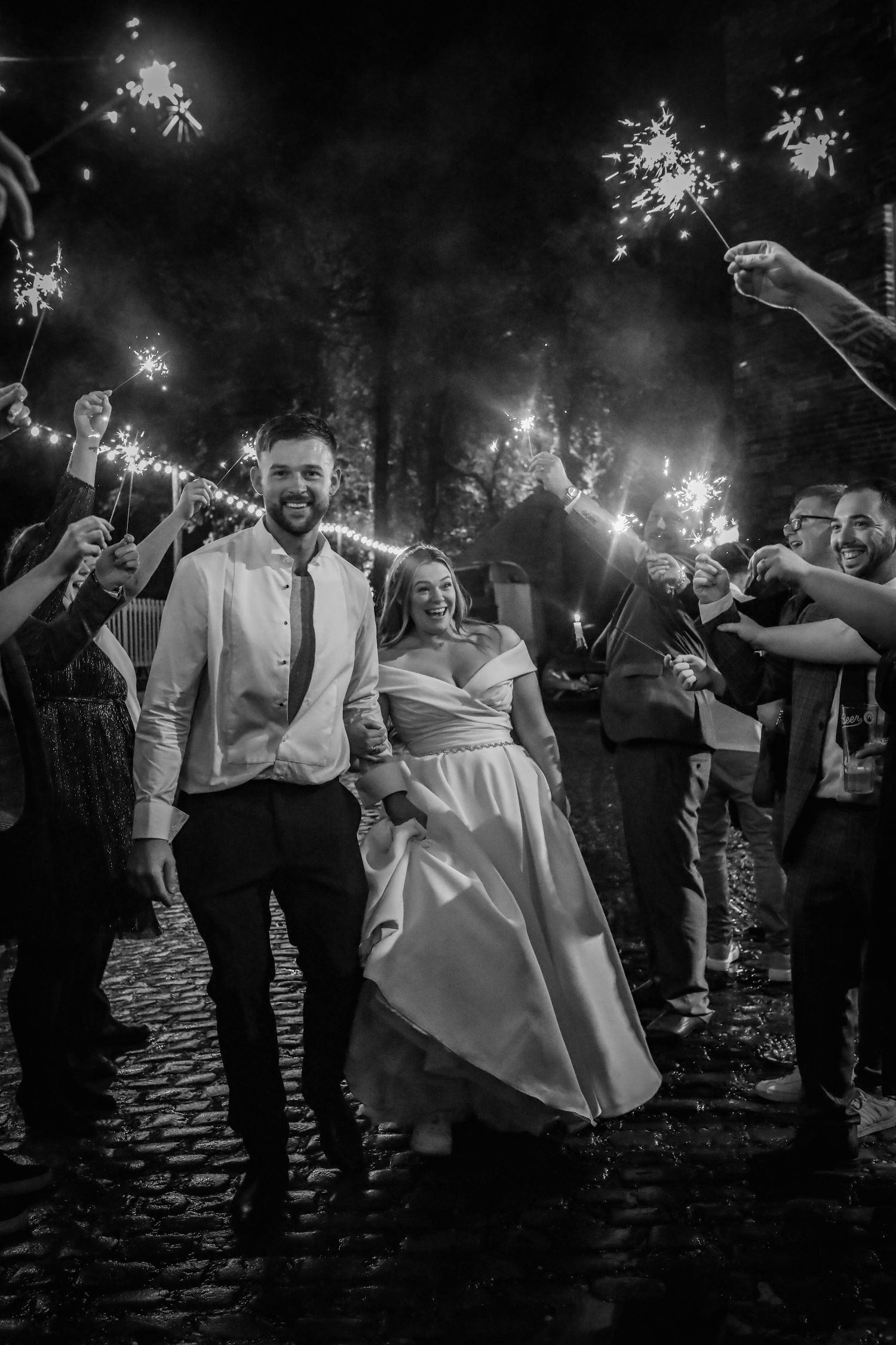 Black and white photo of wedding celebration with guests holding sparklers.