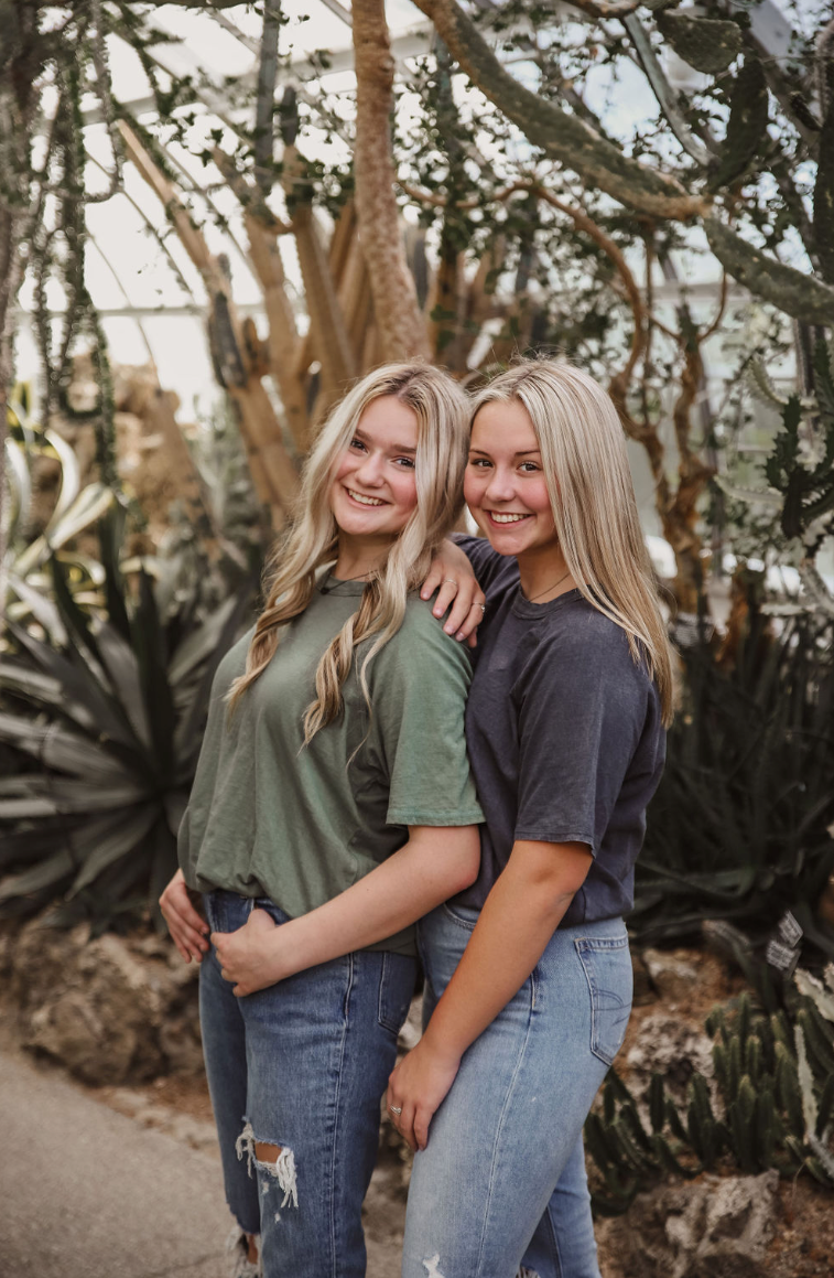 Casual outdoor portrait of two friends in denim and t-shirts posing together.