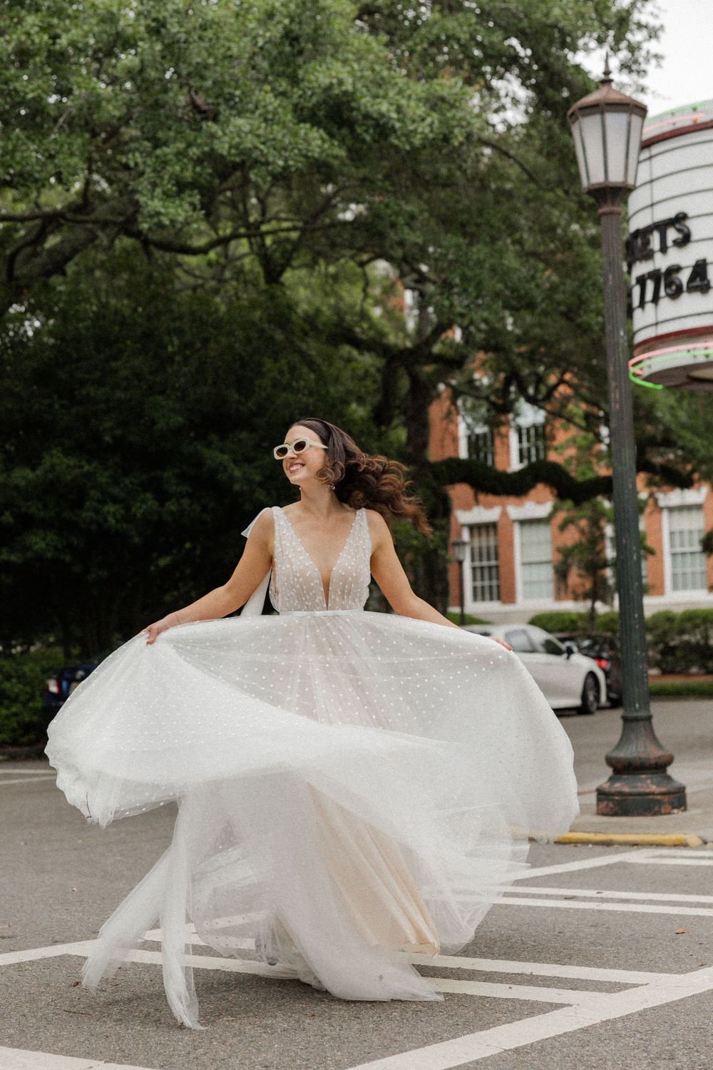 Wedding dress flowing dramatically in the wind on a city street with classic architecture.