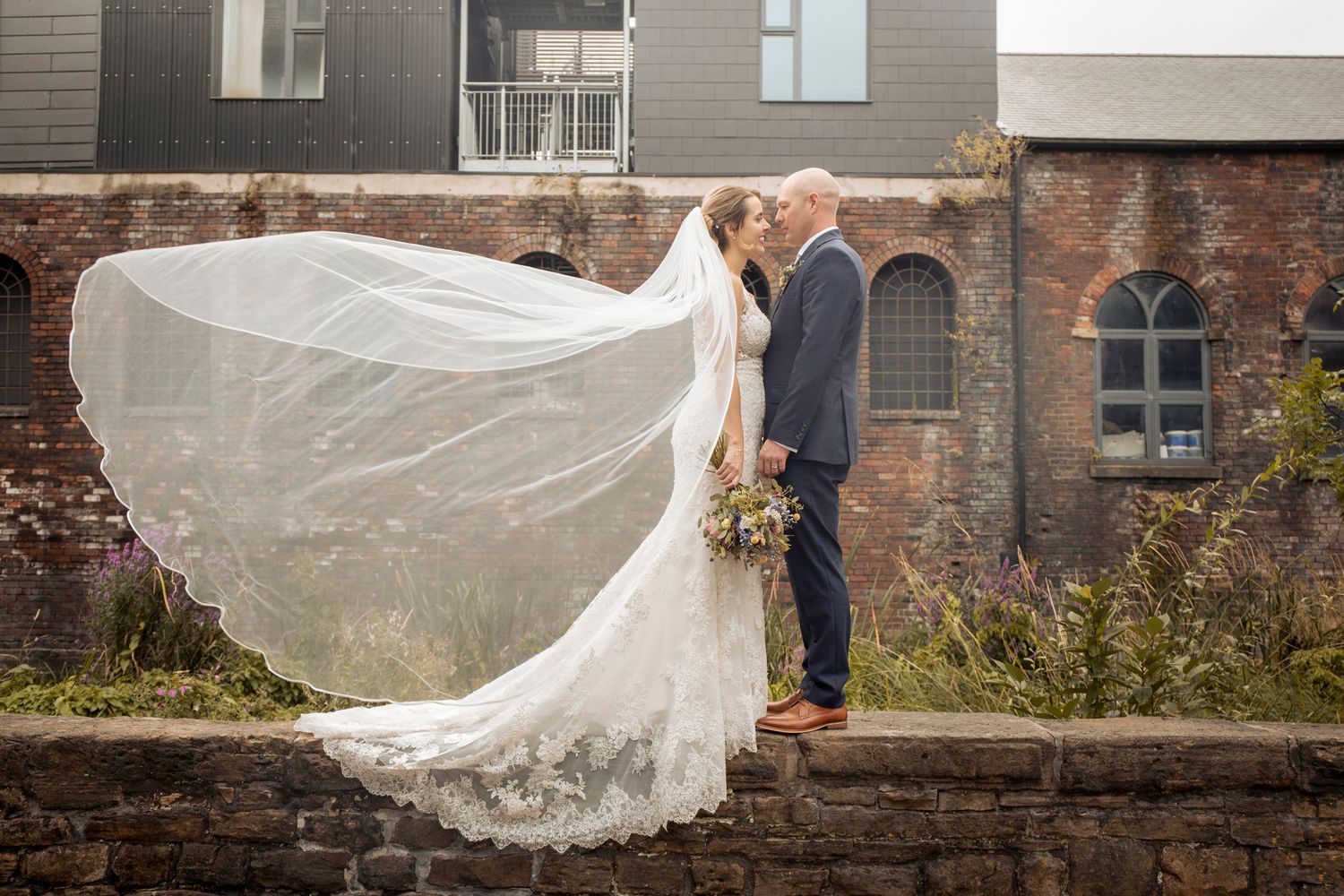 wedding photography at kelham throwing the wedding veil by the indistrial backdrop of kelham island sheffield