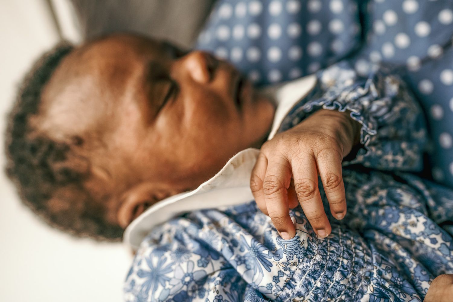 Close-up of newborn baby with hand and fingers in focus