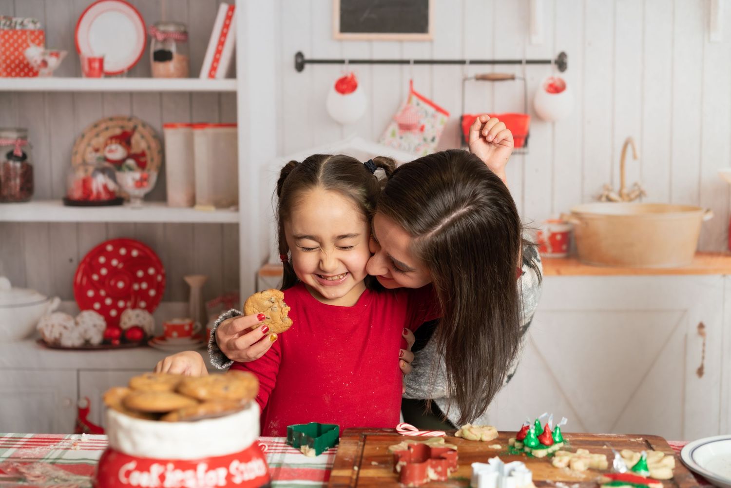 A festive holiday kitchen scene with baking cookies and red Christmas decorations on display.