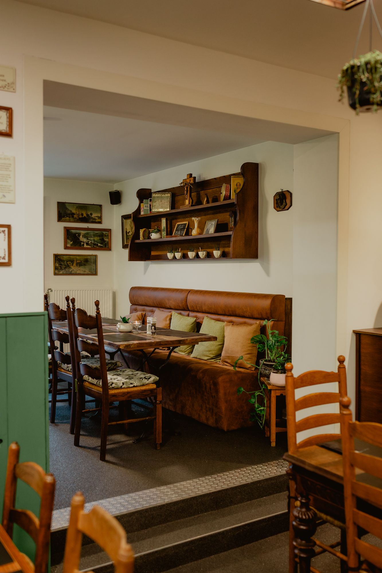 Cozy restaurant interior with wooden chairs and leather booth seating beneath decorative wall shelving.