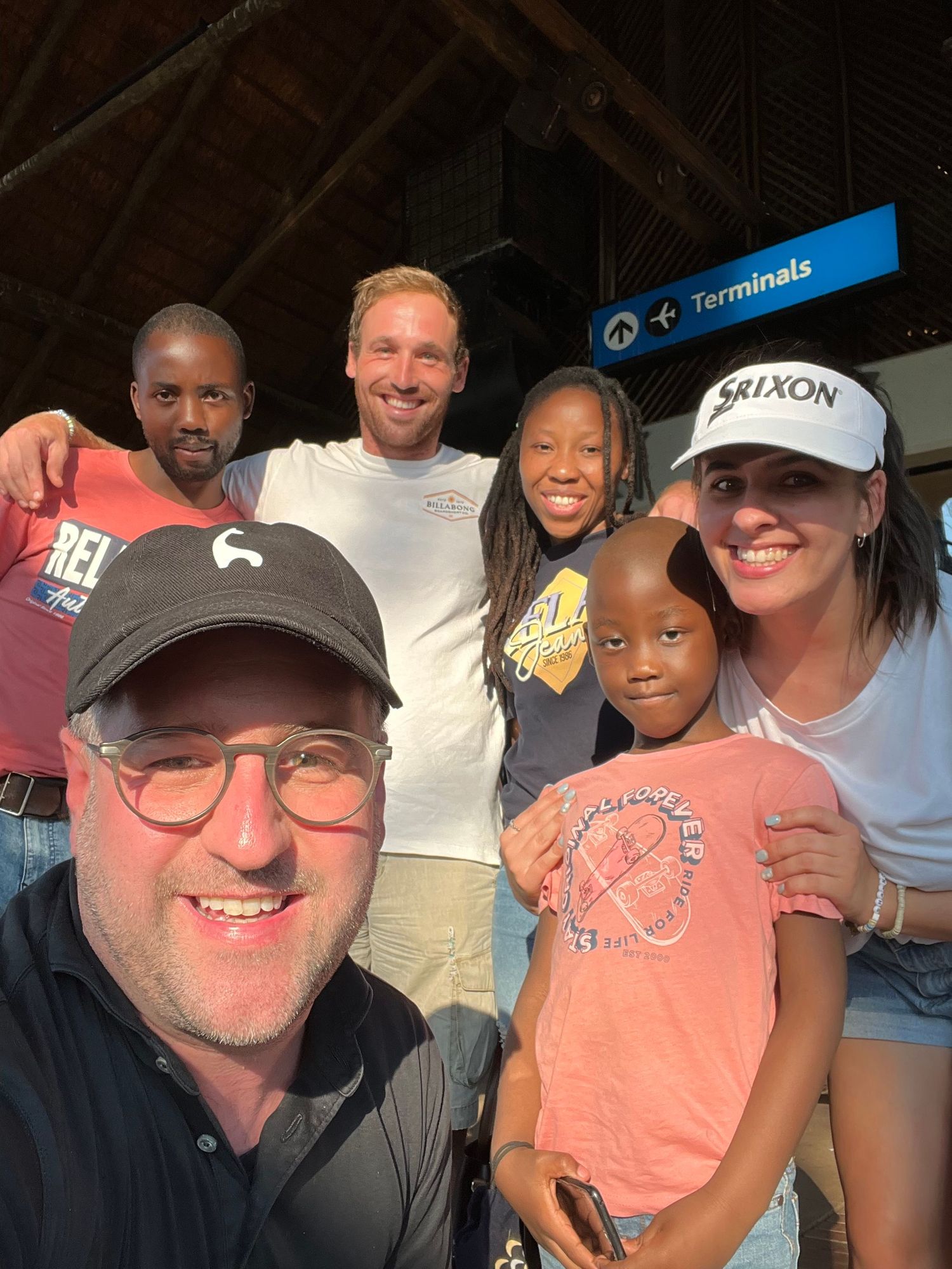 Group gathered at an airport terminal wearing casual attire.