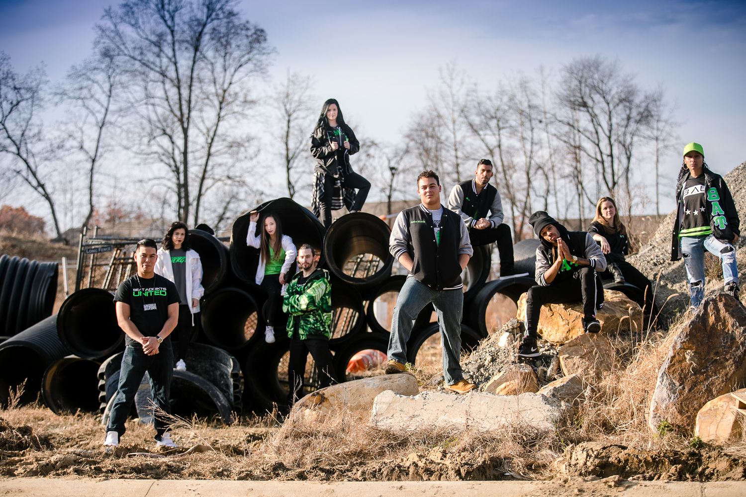 A group wearing green stands on dirt mounds outdoors against a backdrop of bare trees.