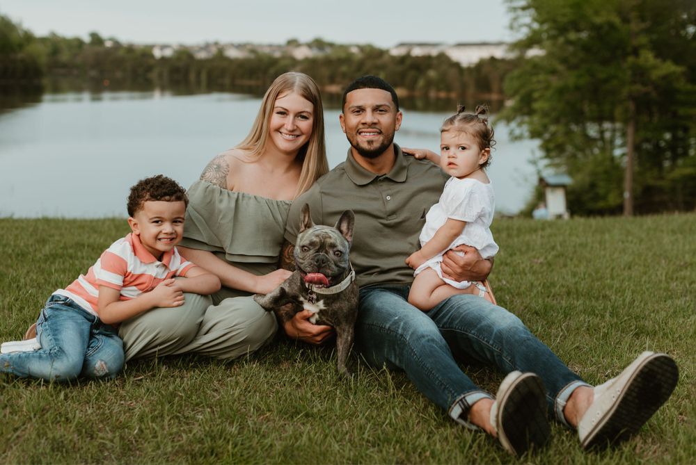 Family relaxes together on grass during casual outdoor photo session.