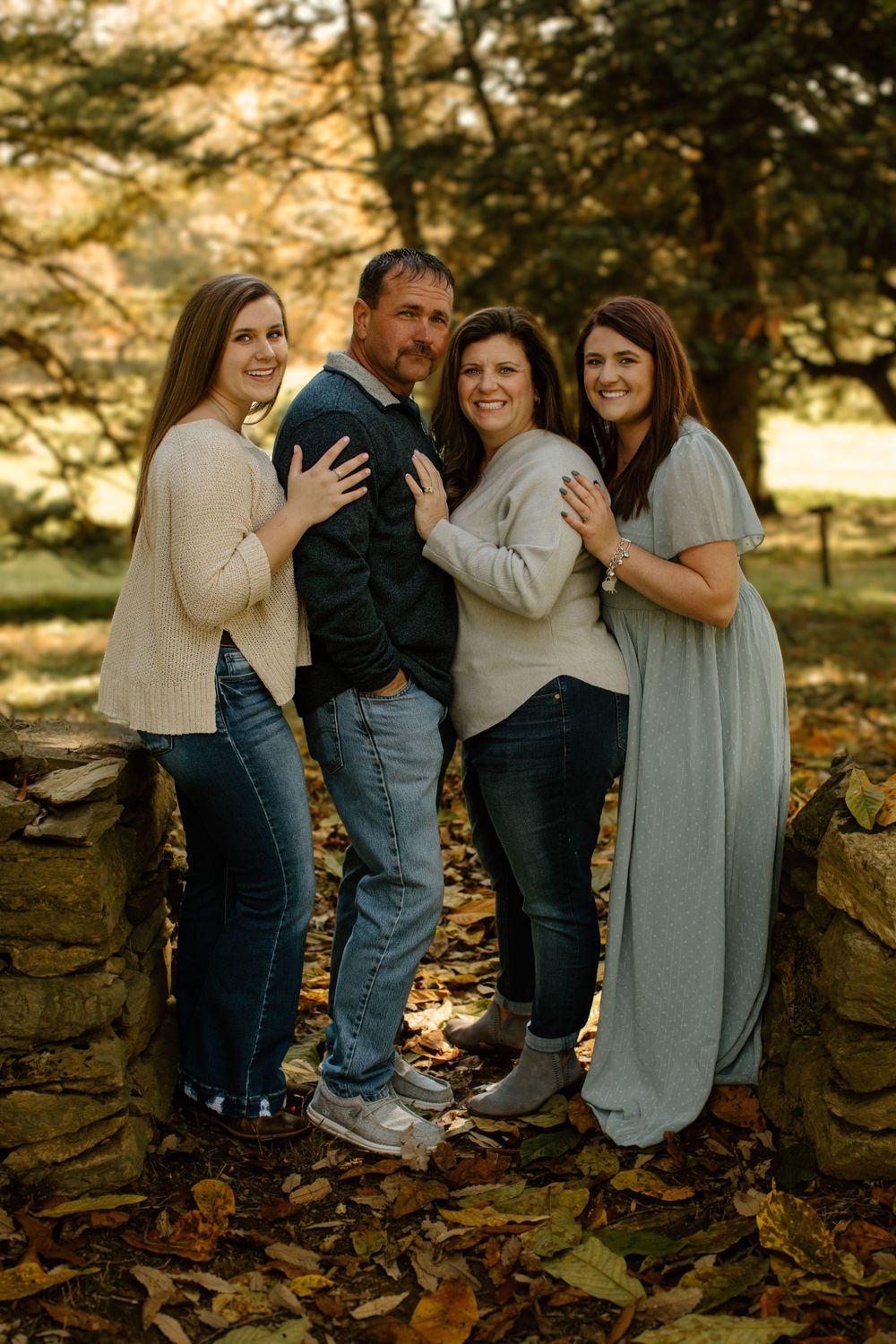 A family poses together against a stone wall during golden hour.